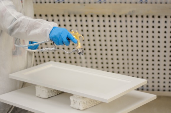 spraying white paint onto a shaker cabinet door